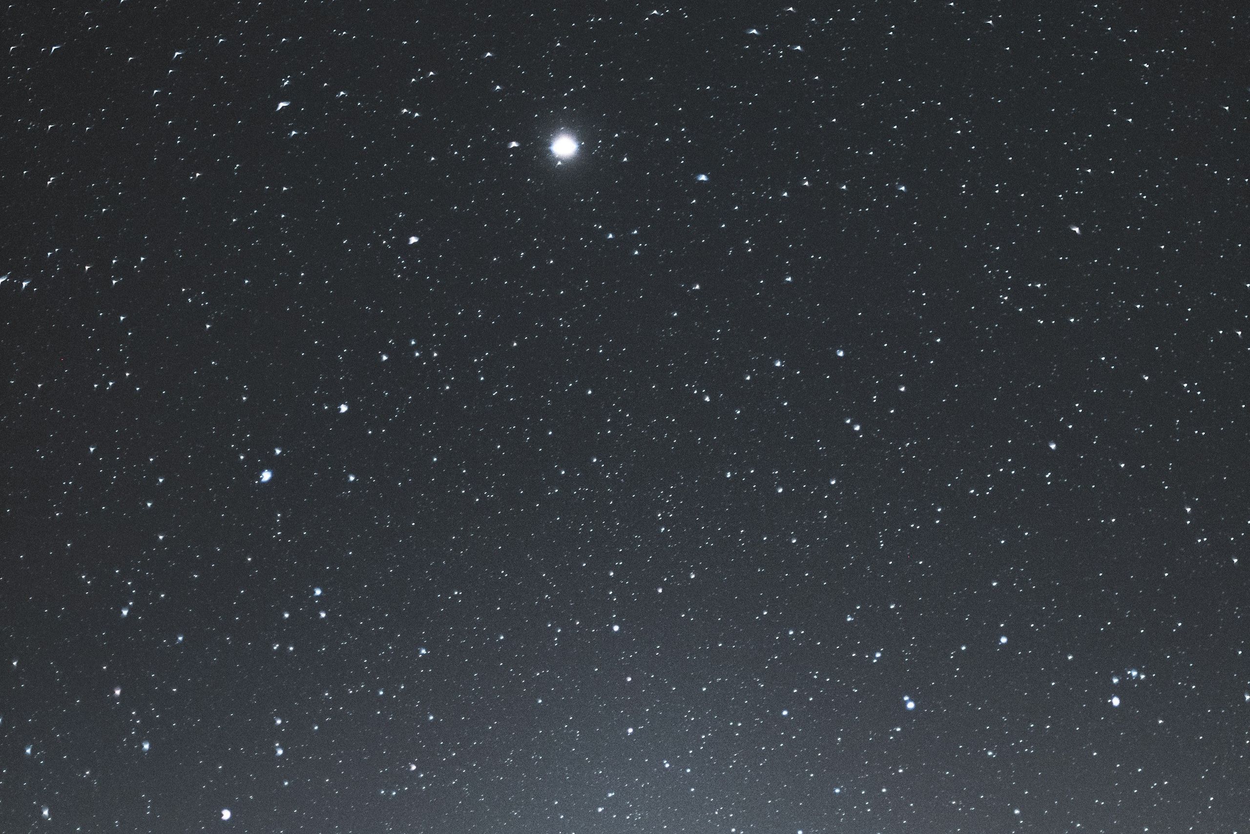 A bright star above a snow-covered mountain peak at night